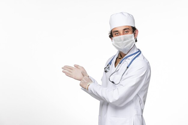 Вид спереди мужчина-врач в медицинском костюме с маской в качестве защиты от covid на белой стене, пандемическая медицина вируса коронавируса