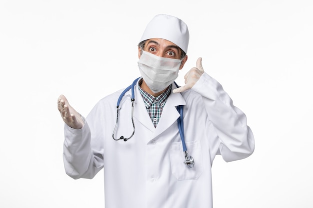 Free photo front view male doctor in medical suit with mask due to covid- on white surface