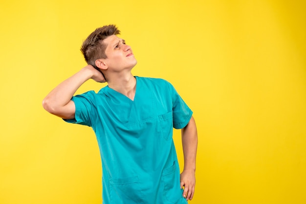 Front view of male doctor in medical suit on a yellow wall
