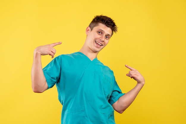 Вид спереди мужского врача в медицинском костюме на желтой стене