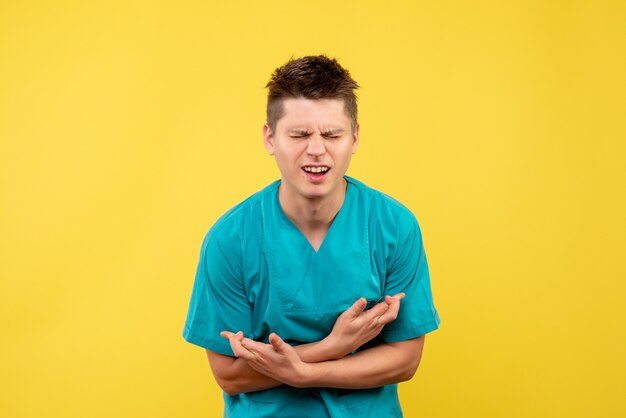 Front view of male doctor in medical suit on a yellow wall