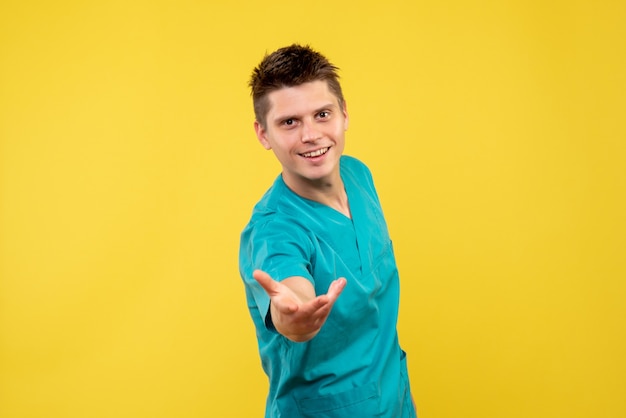 Вид спереди мужского врача в медицинском костюме на желтой стене