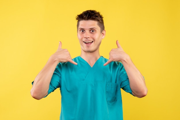 Front view of male doctor in medical suit on yellow wall