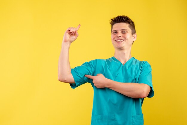 Front view of male doctor in medical suit on yellow wall