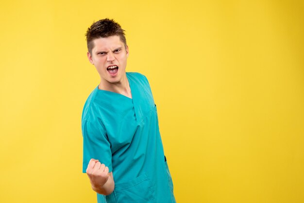 Front view of male doctor in medical suit on yellow wall