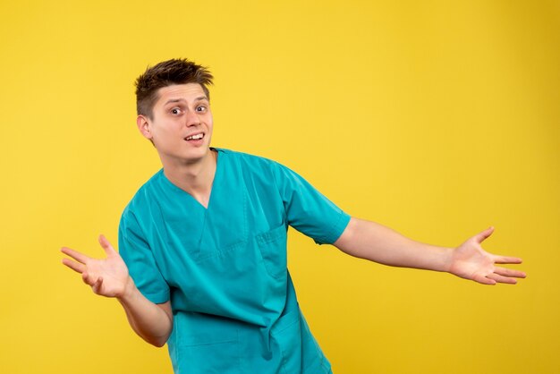 Front view of male doctor in medical suit on yellow wall