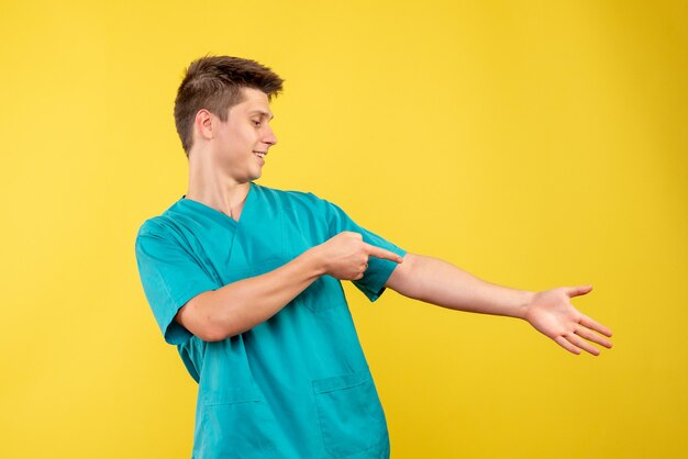 Front view of male doctor in medical suit on yellow wall