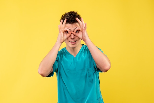 Front view of male doctor in medical suit on yellow wall