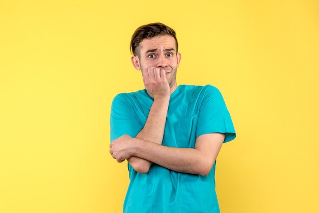 Front view of male doctor nervous on yellow wall