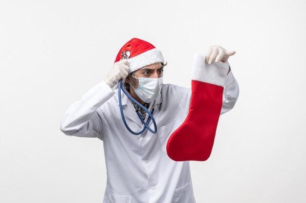 Front view male doctor observing holiday sock on white desk covid virus holiday health