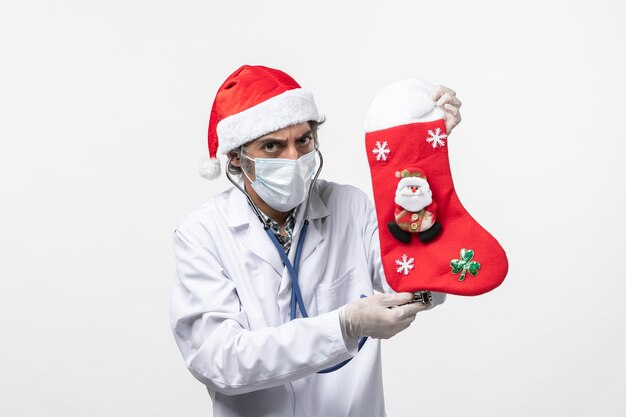 Front view male doctor observing holiday sock on white desk covid virus holiday