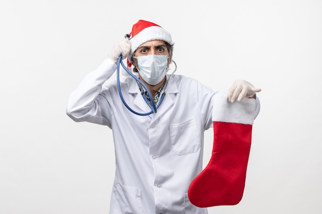 白い壁のcovidウイルス休日の健康で休日の靴下を観察する正面図男性医師