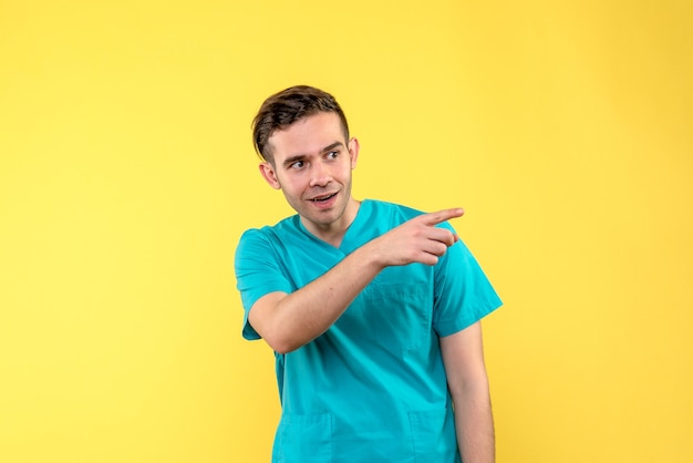 Вид спереди мужского врача, указывающего на желтую стену
