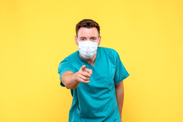 Front view of male doctor pointing on yellow wall