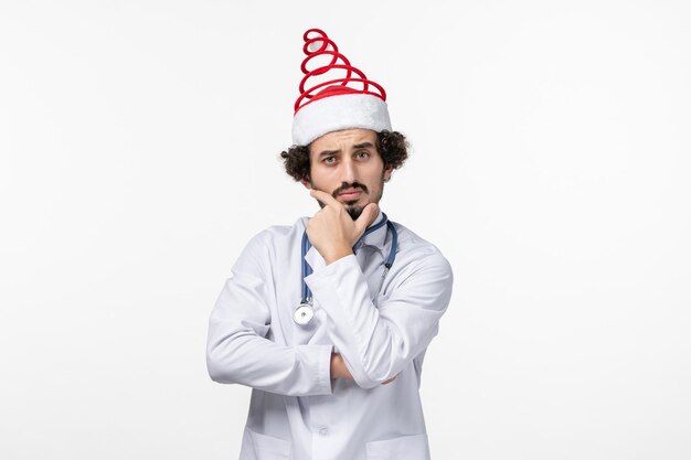 Front view of male doctor posing on white wall