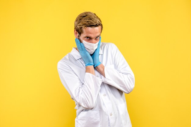 Front view male doctor posing on a yellow background pandemic medic health covid- virus