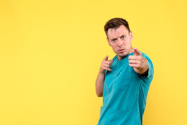 Front view of male doctor posing on a yellow wall