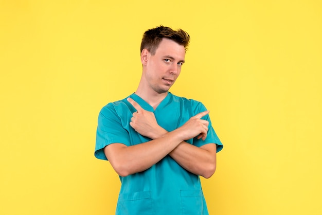 Front view of male doctor posing on yellow wall