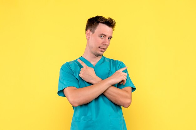 Front view of male doctor posing on yellow wall