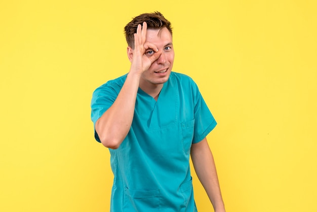 Front view of male doctor posing on yellow wall