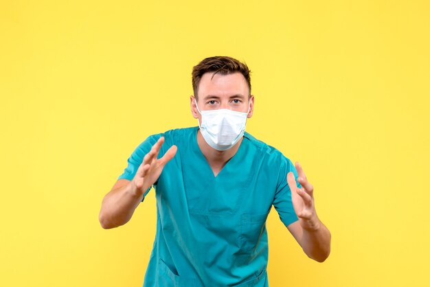 Вид спереди мужчины-врача в защитной маске на желтой стене