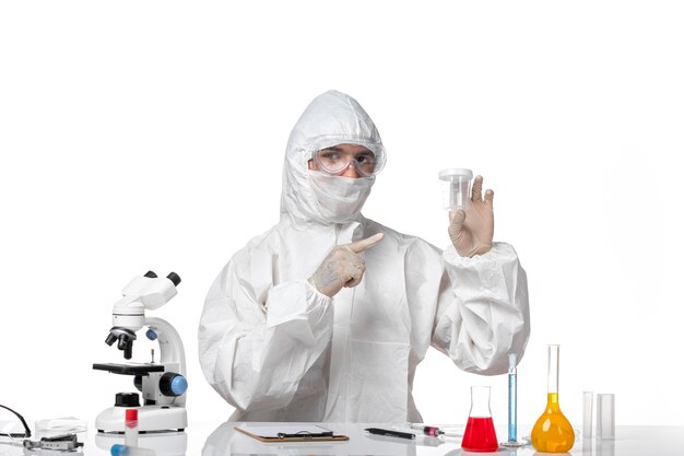 Front view male doctor in protective suit holding empty flask on light white space