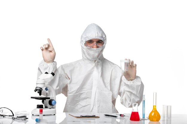 Front view male doctor in protective suit holding empty flask on a white space