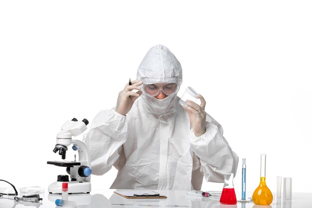 Front view male doctor in protective suit holding empty flask and writing on white space