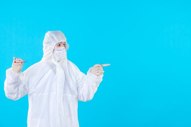 Front view male doctor in protective suit holding flask on blue