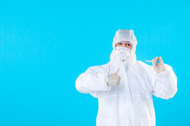 Front view male doctor in protective suit holding flask on blue