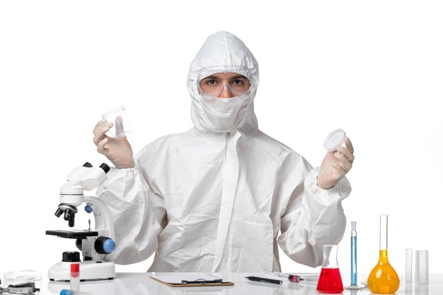 Front view male doctor in protective suit holding flask on a white space