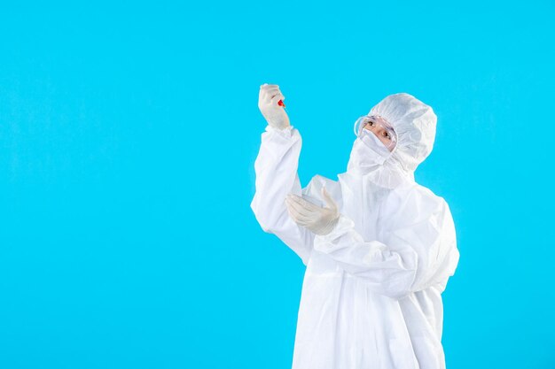 Front view male doctor in protective suit holding injection on blue