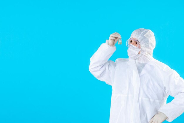 Front view male doctor in protective suit and mask on blue