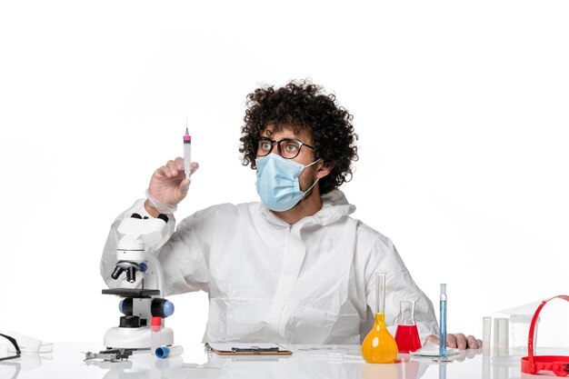 Front view male doctor in protective suit and mask holding injection on white