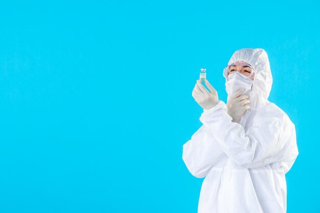 Front view male doctor in protective suit and mask holding little flask on blue