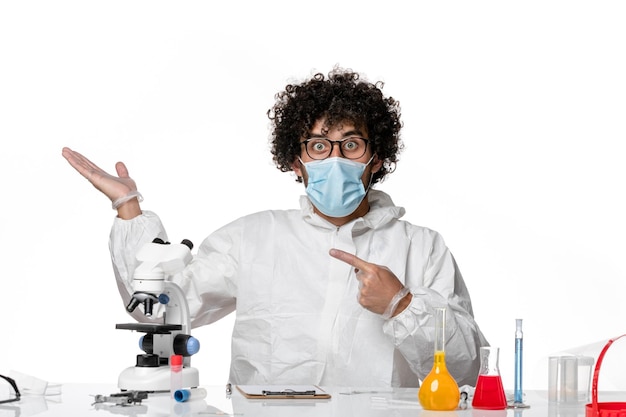 Front view male doctor in protective suit and mask just sitting with solutions on white