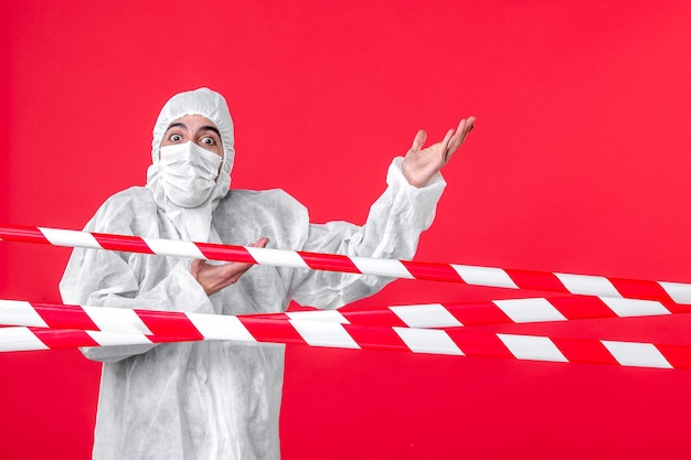 Вид спереди врач-мужчина в защитном костюме и маске на красном фоне лечебная больница covid-карантинная цветовая изоляция