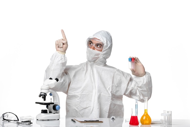 Free photo front view male doctor in protective suit with mask due to covid holding flasks on a light-white space