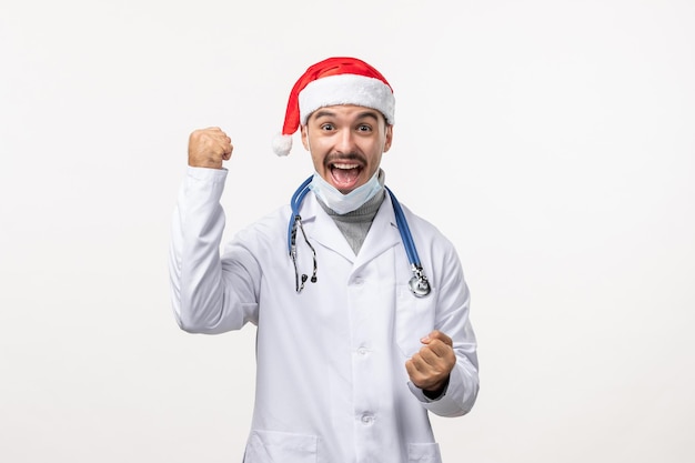 Front view of male doctor rejoicing on white wall