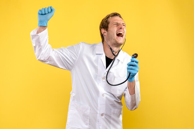 Front view male doctor screaming on a yellow background virus health emotion medic