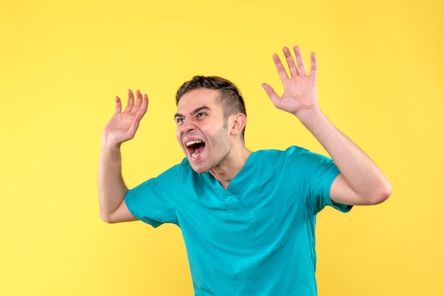 Front view of male doctor screaming on yellow wall
