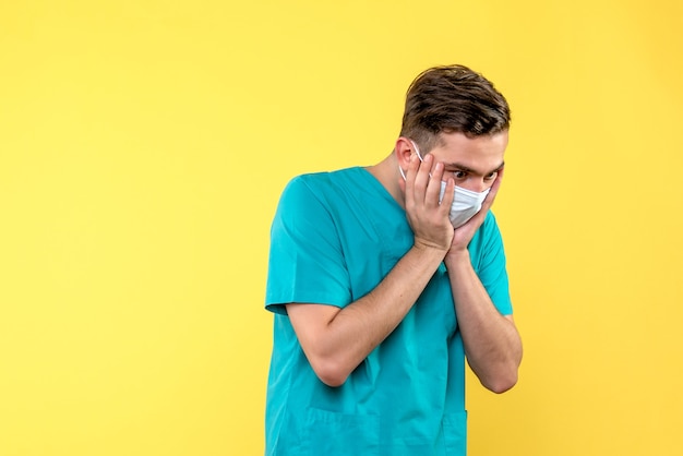Front view of male doctor shocked on yellow wall