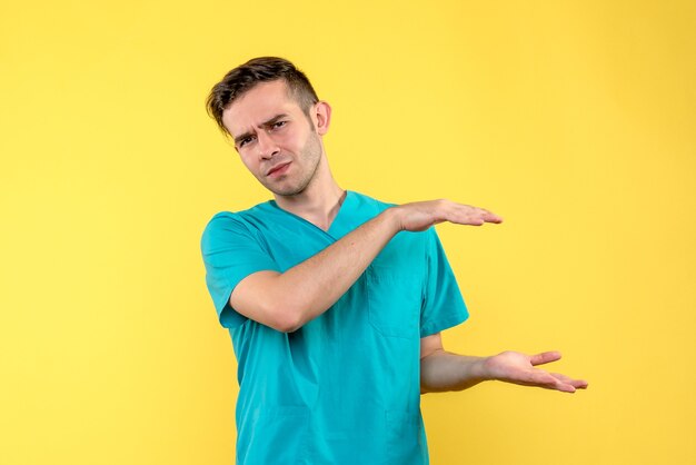 Front view of male doctor showing size on yellow wall