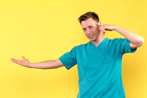 Front view of male doctor slightly smiling on yellow wall