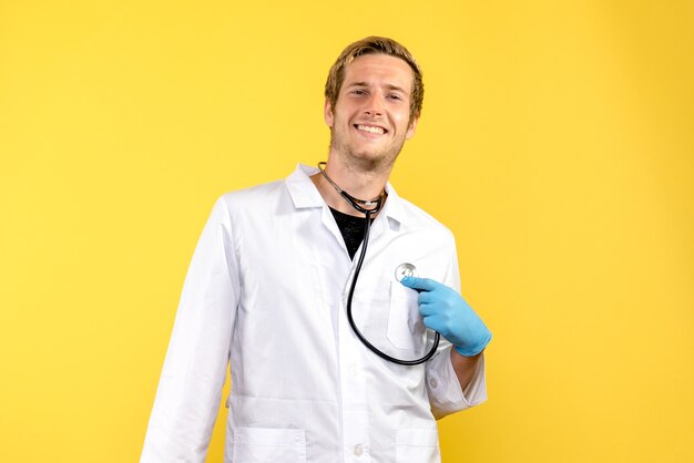 黄色の背景の健康ウイルスの薬の感情に笑顔の正面図男性医師