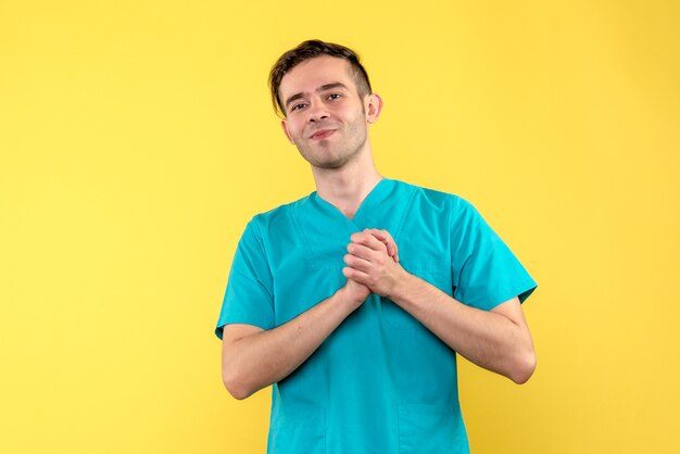 Front view of male doctor smiling on a light yellow wall