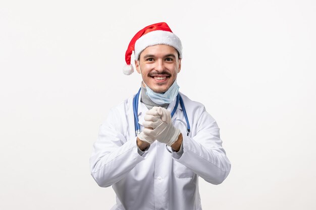 Вид спереди мужского врача, улыбаясь на белой стене