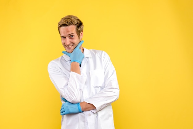 Вид спереди мужчина-врач, улыбаясь на желтом фоне, пандемия здоровья медика
