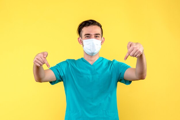 Front view of male doctor smiling on yellow wall