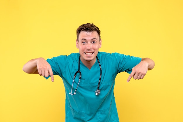 Front view of male doctor smiling on yellow wall